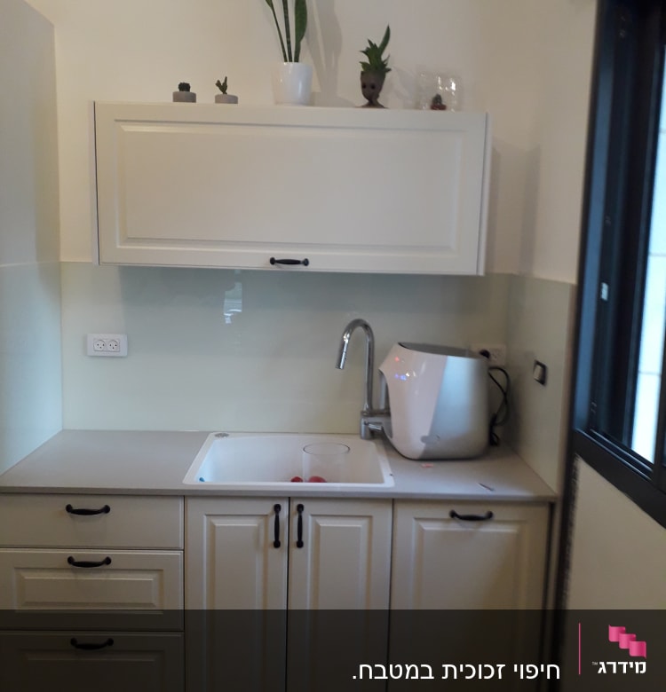 כוס זכוכית בכיור מטבח לבן